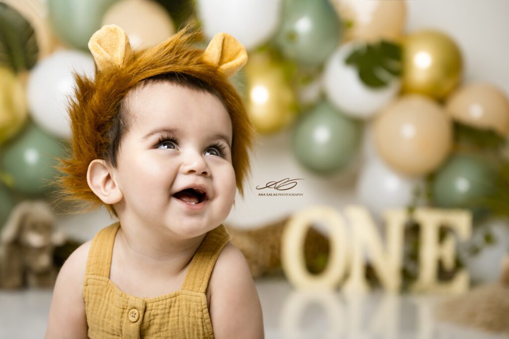 Little boy in a lion outfit looking up and smiling during his cake smash photoshoot in Edmonton