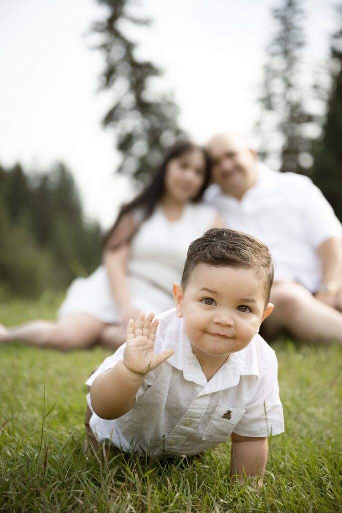 little boy crawling toward the camera with his parents behind him during their Family Photography Session in Edmonton