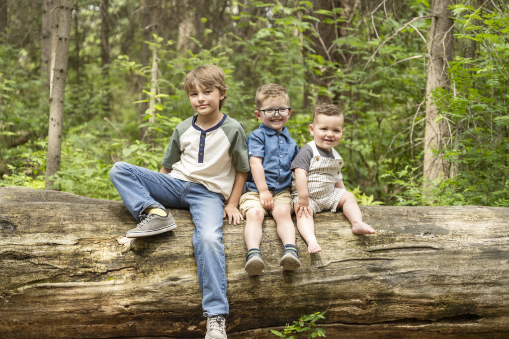 three young boys sitting on a log during their Family Photography Session in Edmonton