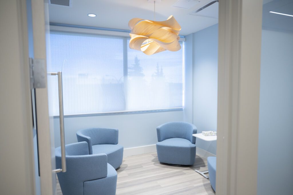 A consultation room at Alberta Reproductive Centre with blue swivel chairs and an artistic chandelier