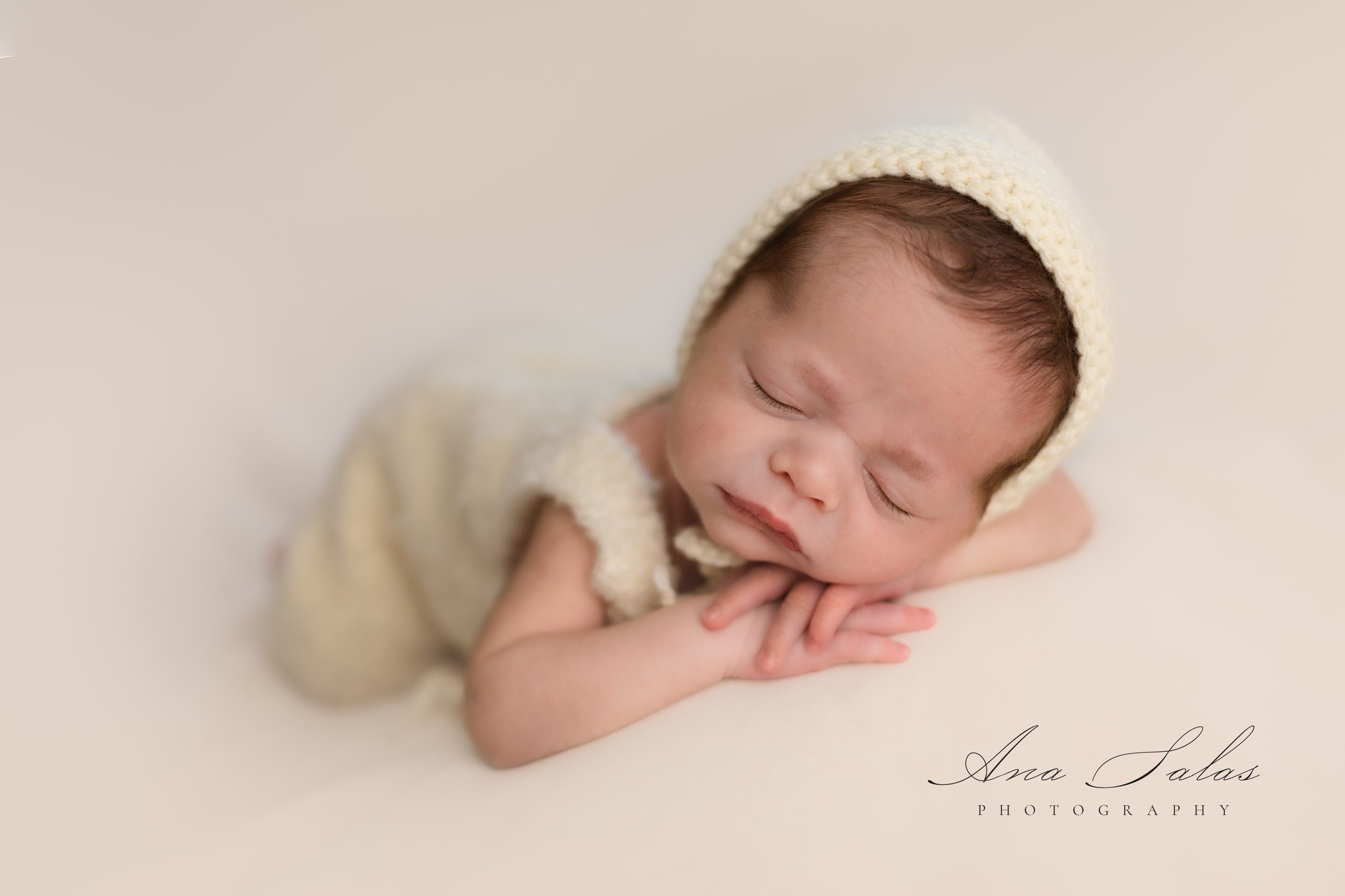 A newborn baby sleeps in a yellow onesie and matching bonnet in a studio while using edmonton diaper service