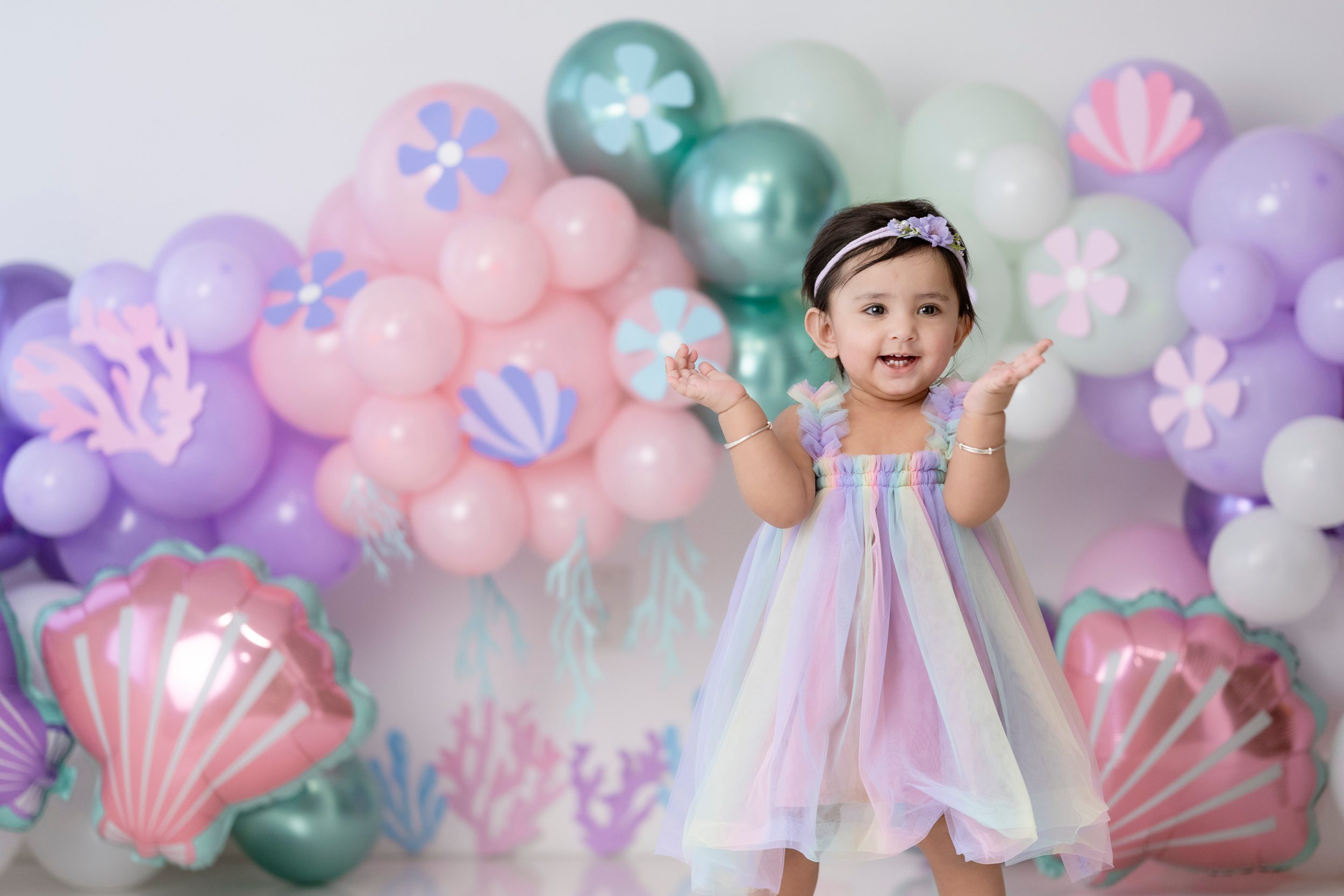 A happy toddler girl claps while standing in a studio for her mermaid themed birthday before some Mommy and Me classes Edmonton