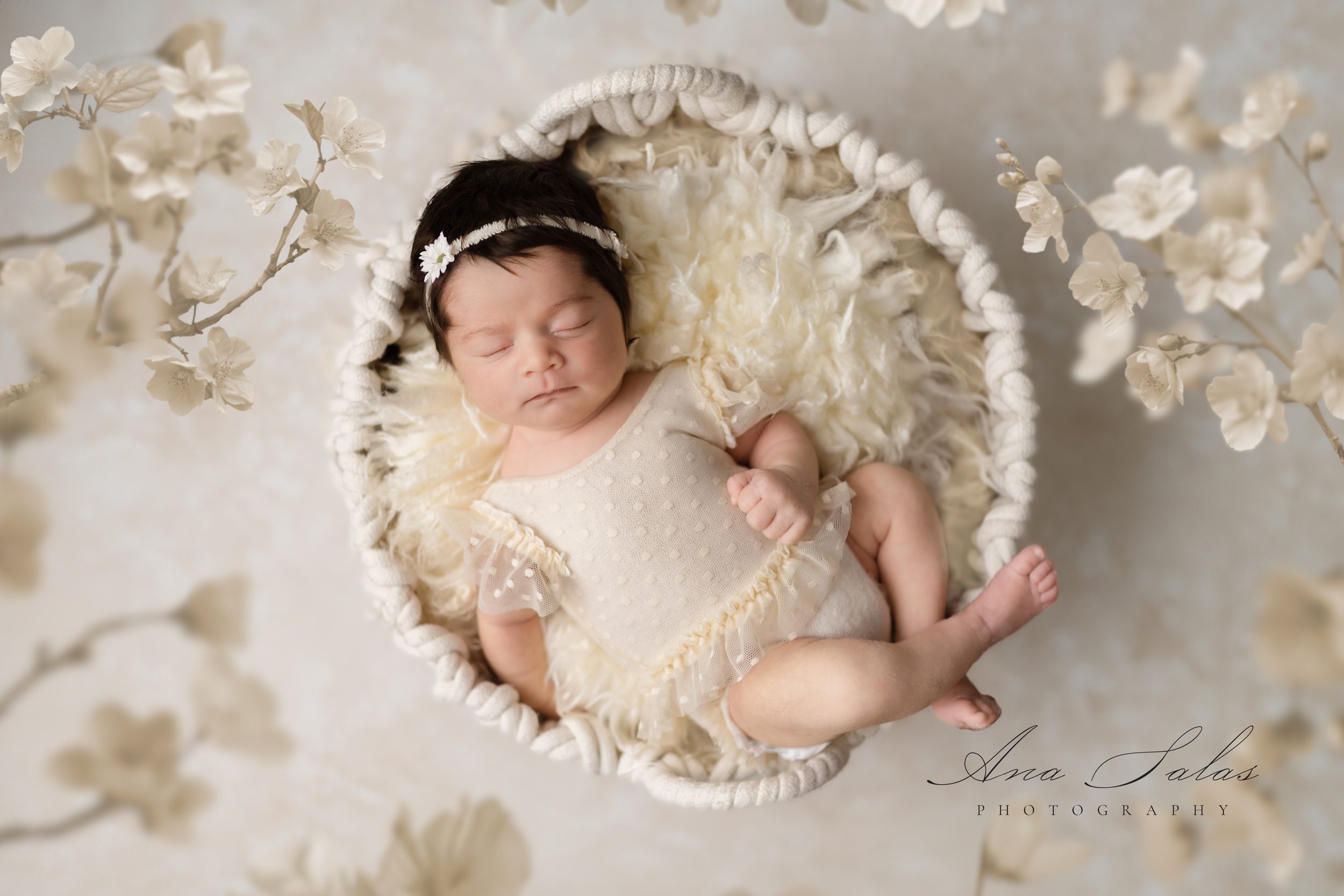 A sleeping newborn baby lays in a woven basket on a fur blanket