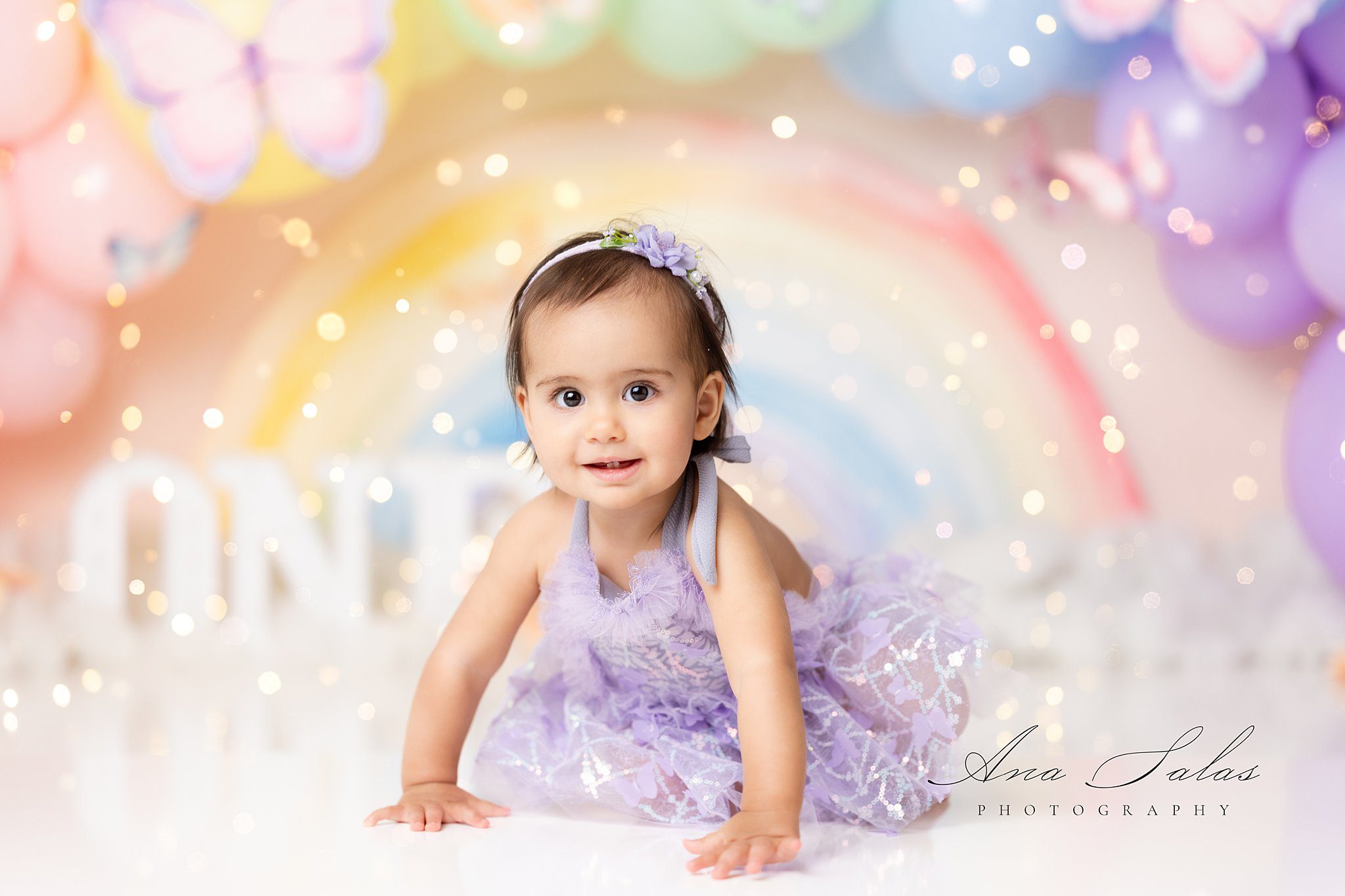 A young toddler girl in a purple butterfly dress crawl on a studio floor after meeting an au pair edmonton