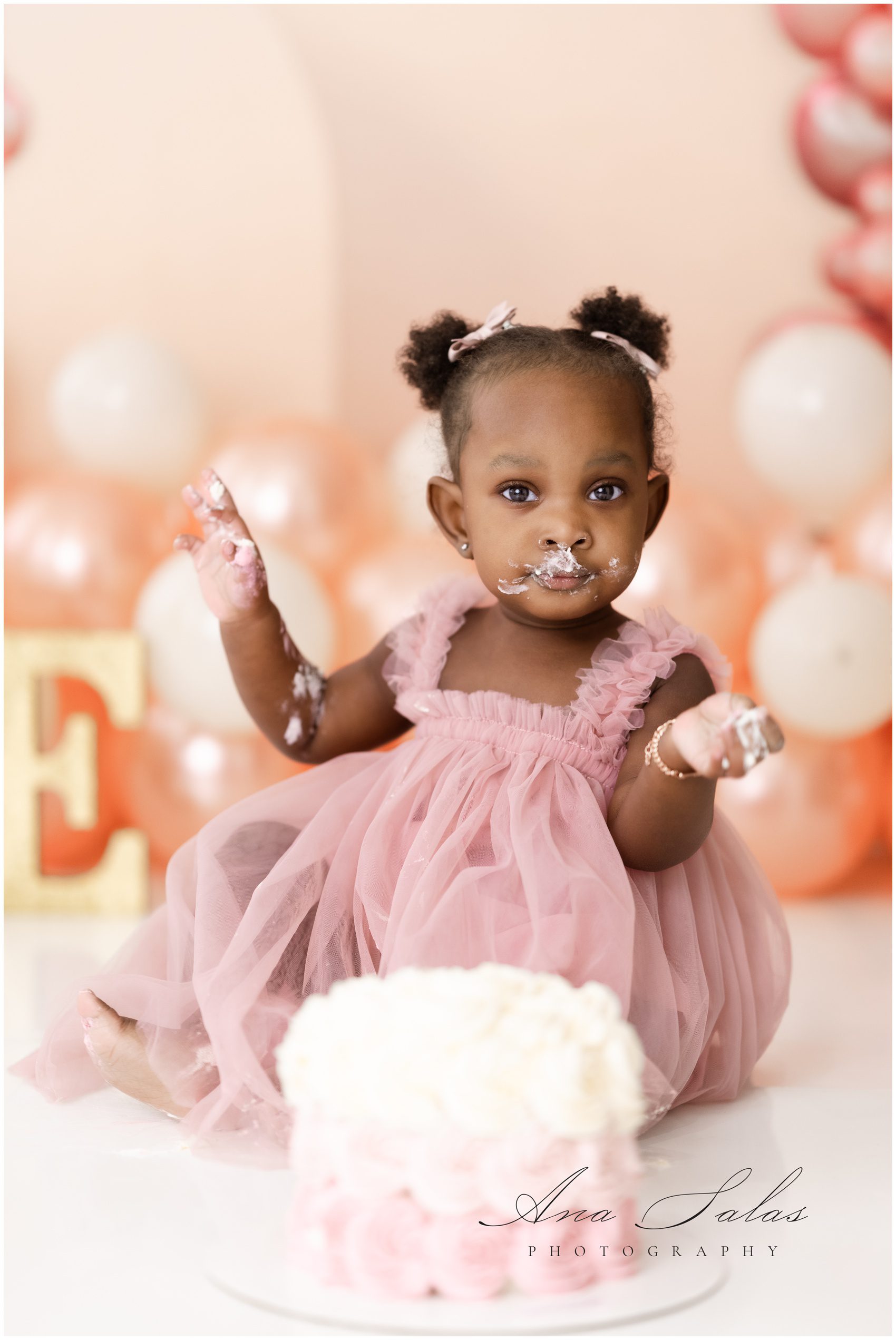 A toddler girl in a pink dress smashes a cake for her birthday before shopping for childrens clothing edmonton