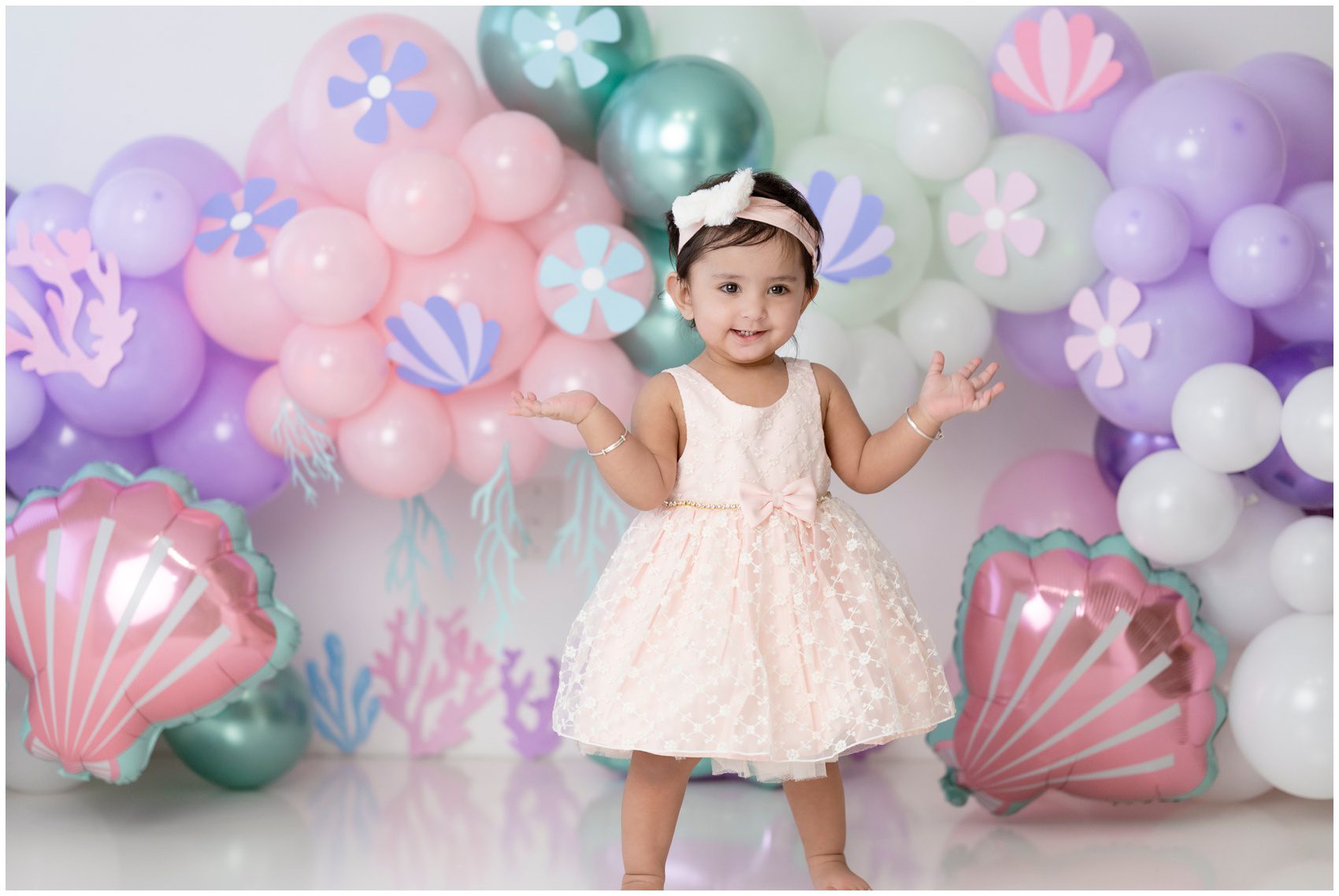 A toddler girl in a sea themed studio with balloons dances in a pink dress after shopping for childrens clothing edmonton