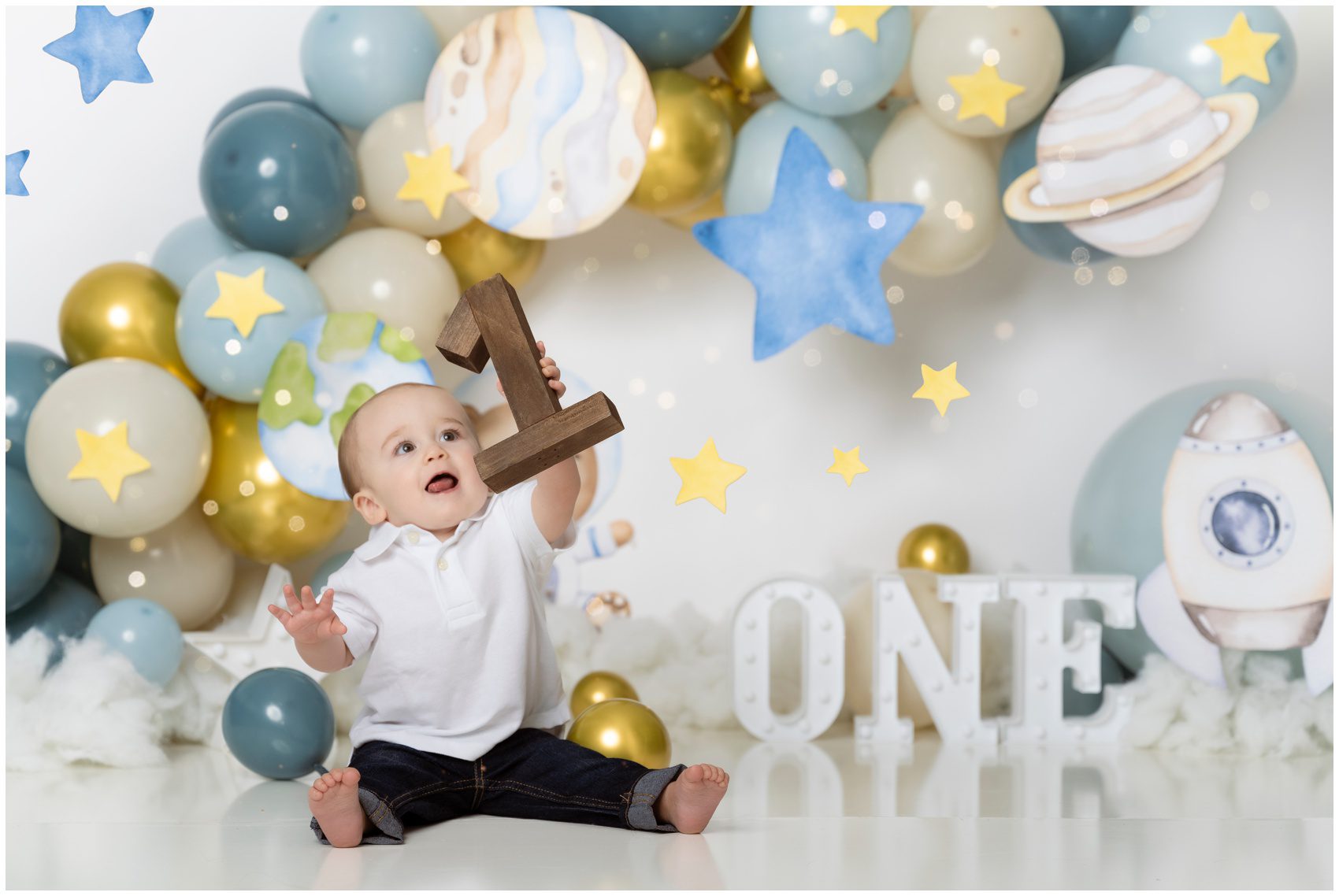 A toddler boy lifts a wooden number 1 while sitting in a decorated studio space themed before visiting edmonton toy stores