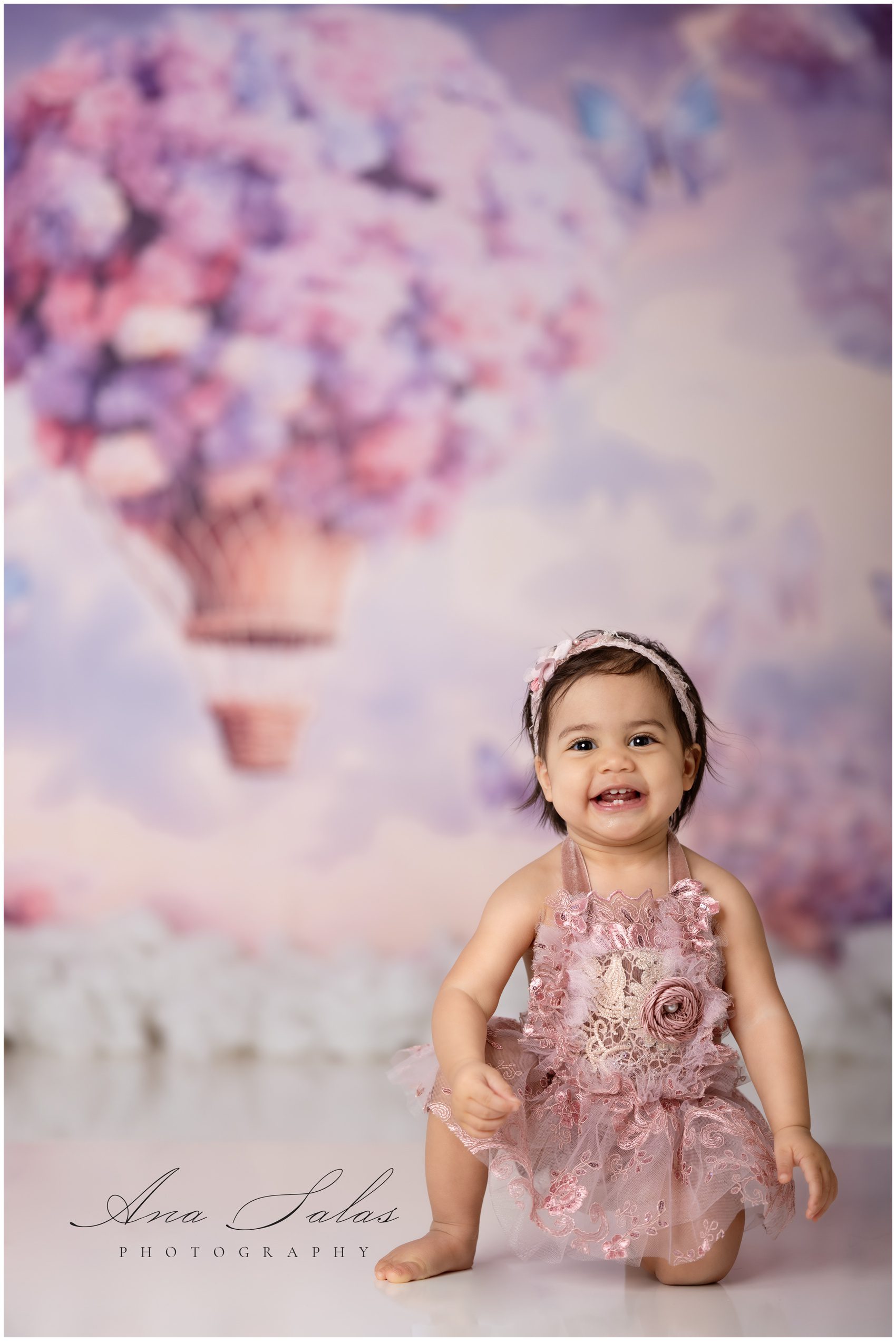 A happy toddler girl in a pink flower dress plays in a studio before visiting indoor playgrounds edmonton