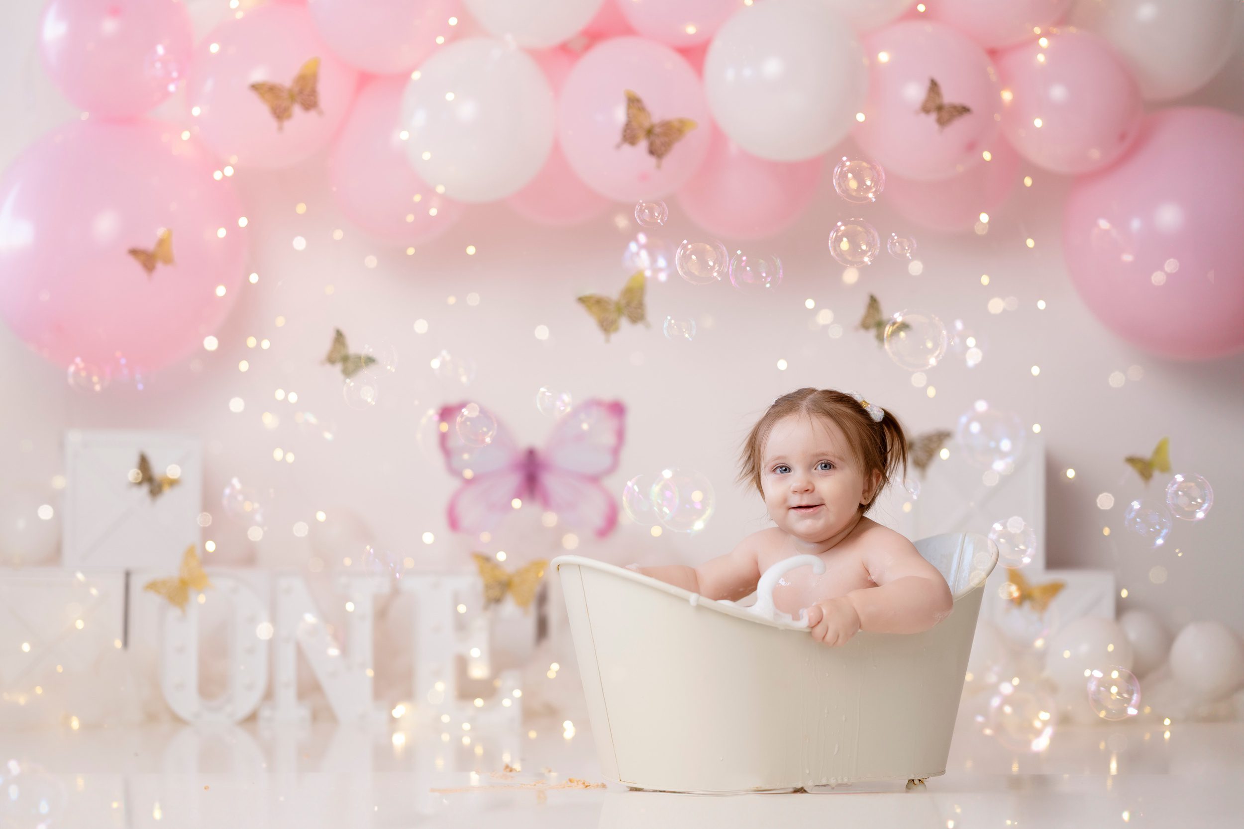 A baby girl sits in a tiny bathtub surrounded by floating bubbles for her birthday after visiting head shoulders knees and toes edmonton