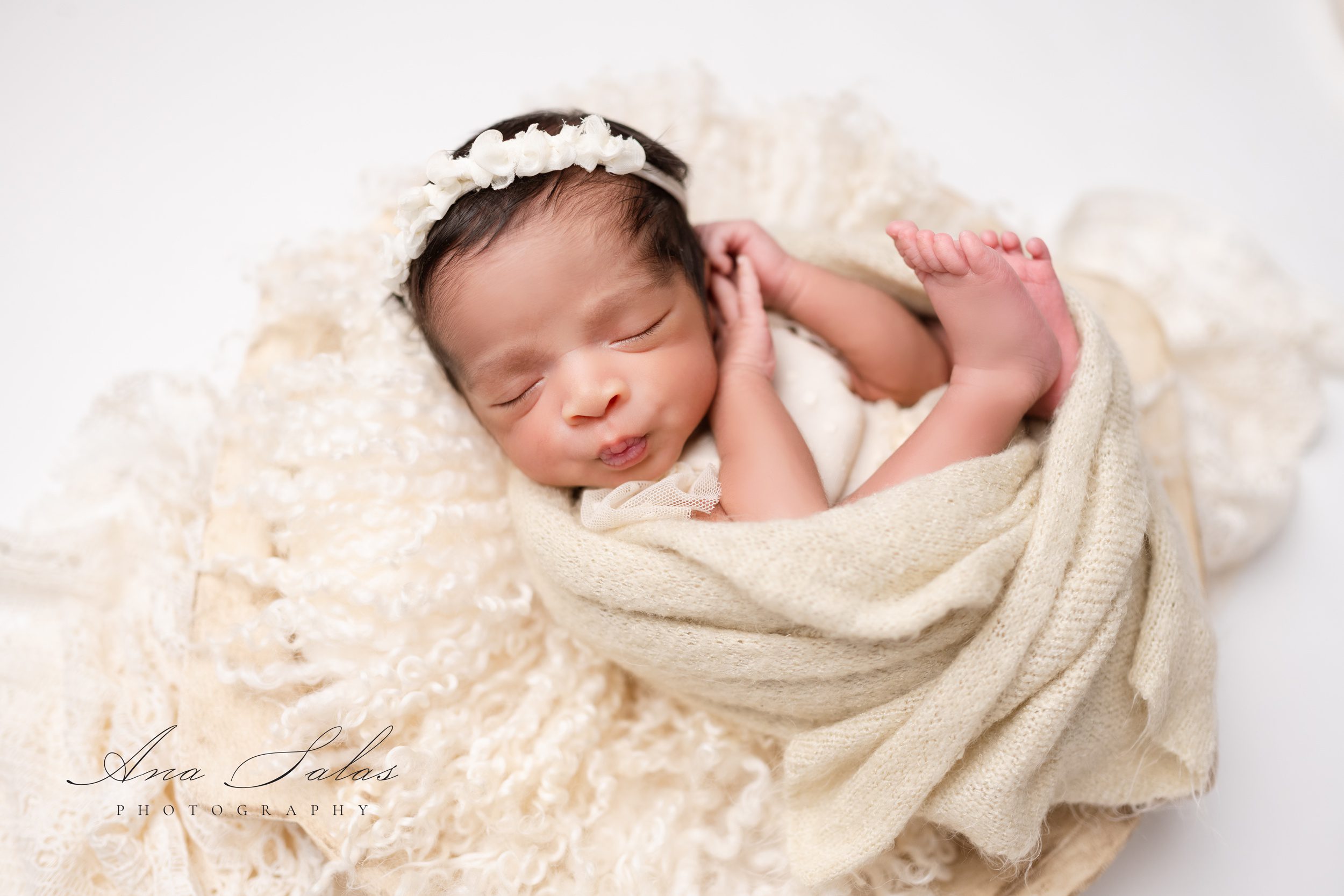 A newborn baby sleeps in a blanket on her back after meeting preferred nannies edmonton