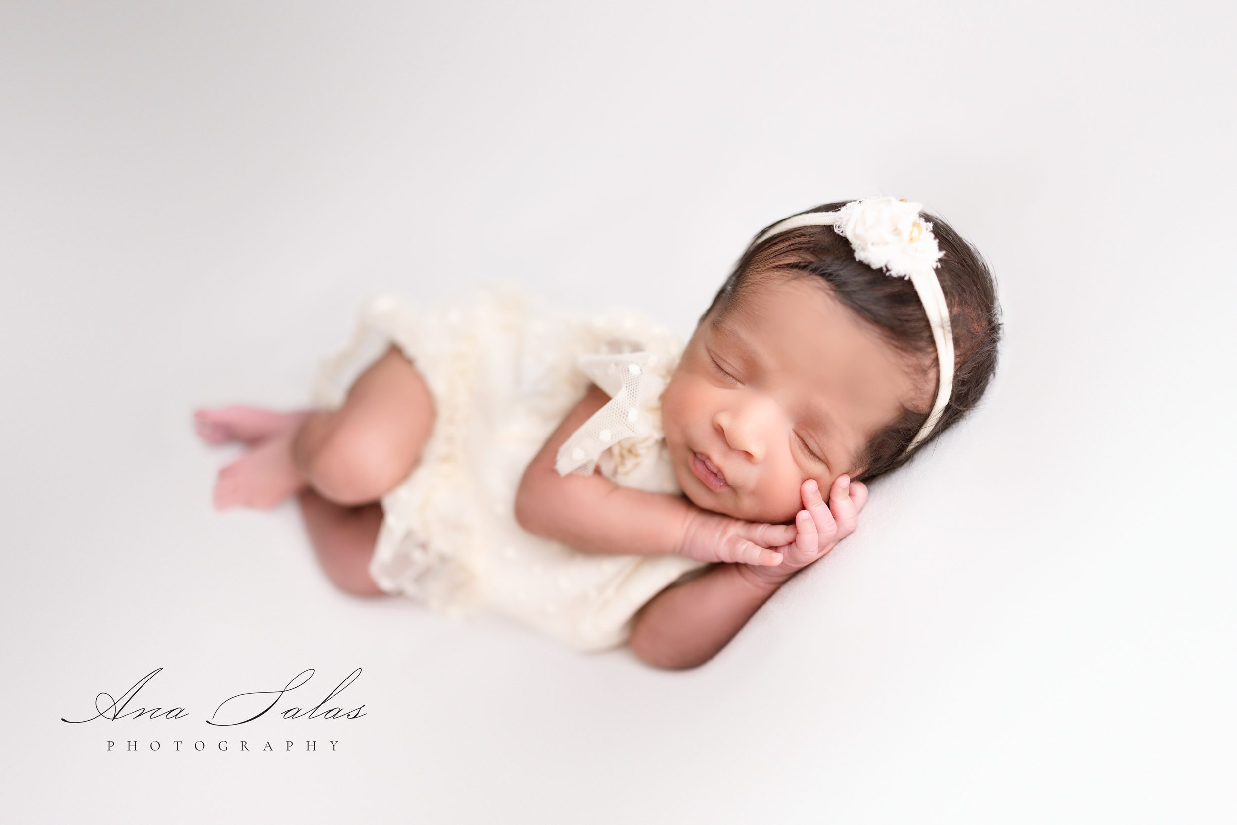 A baby girl sleeps in a white dress and floral headband on her side after meeting preferred nannies edmonton